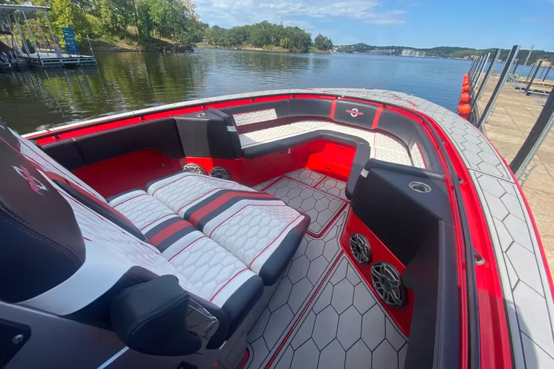 Slide: The Image of 2021 Fountain 34 SC boat interior with red and white seating, docked by a scenic lake. - 31