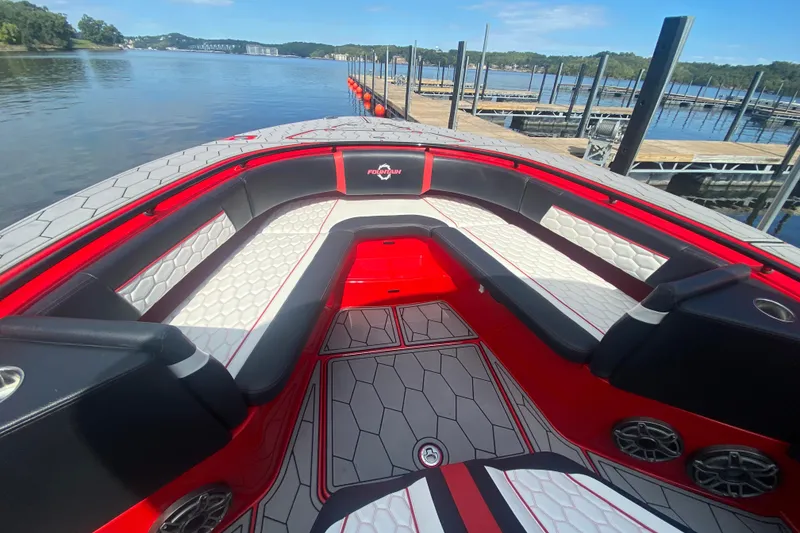Slide: The Image of 2021 Fountain 34 SC boat interior with red and white seating, docked by a serene lake. - 34