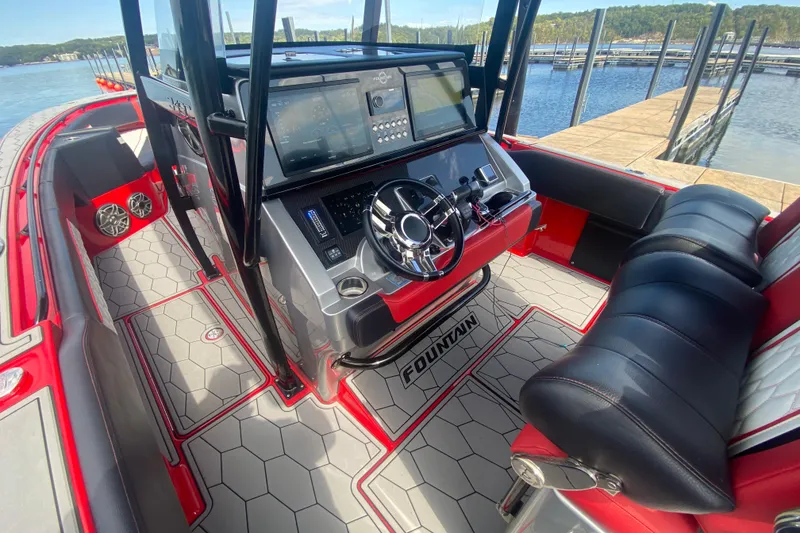 Slide: The Image of 2021 Fountain 34 SC boat interior with modern dashboard and seating, docked by the water. - 39