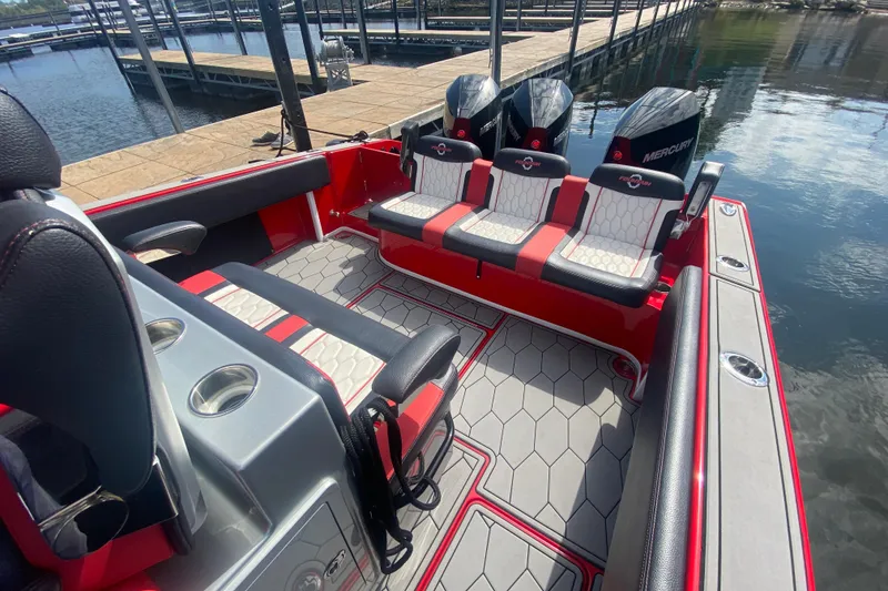 Slide: The Image of 2021 Fountain 34 SC boat interior with red and gray seating, docked by the water. - 40