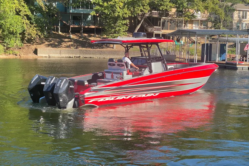 Slide: The Image of Red 2021 Fountain 34 SC boat cruising on a sunny lake near docks. - 8