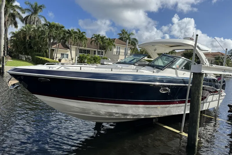 The Image of 2021 Formula 330 Crossover Bowrider OB docked by waterfront homes, under a sunny sky. - 0