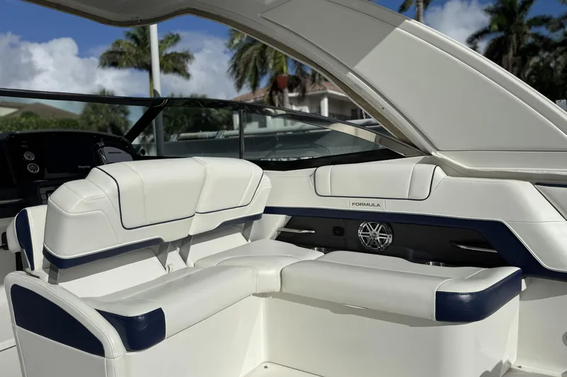 Slide: The Image of 2021 Formula 330 Crossover Bowrider OB interior with white and navy seating, palm trees visible. - 22