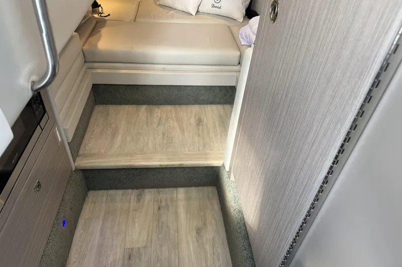 Slide: The Image of 2021 Formula 330 Crossover Bowrider OB interior with wooden steps and cushioned seating. - 48