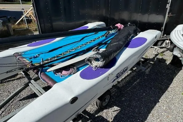 The Image of 2002 Hobie Cat Hobie Club Wave sailboat on trailer, with blue and purple accents. - 0