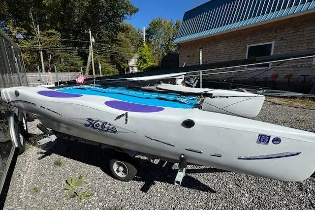 Slide: The Image of 2002 Hobie Cat Hobie Club Wave sailboat on trailer, parked outdoors. - 2