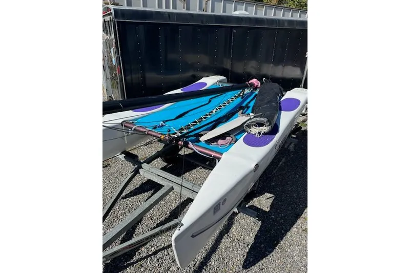 Slide: The Image of 2002 Hobie Cat Hobie Club Wave sailboat on trailer, featuring blue and purple accents. - 4