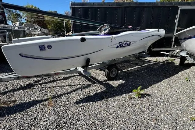 Slide: The Image of 2002 Hobie Cat Hobie Club Wave sailboat on a trailer, parked on gravel. - 5
