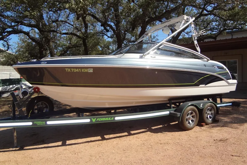 Slide: The Image of 2020 Formula 240 Bowrider boat on trailer, parked in driveway, with blue sky background. - 2