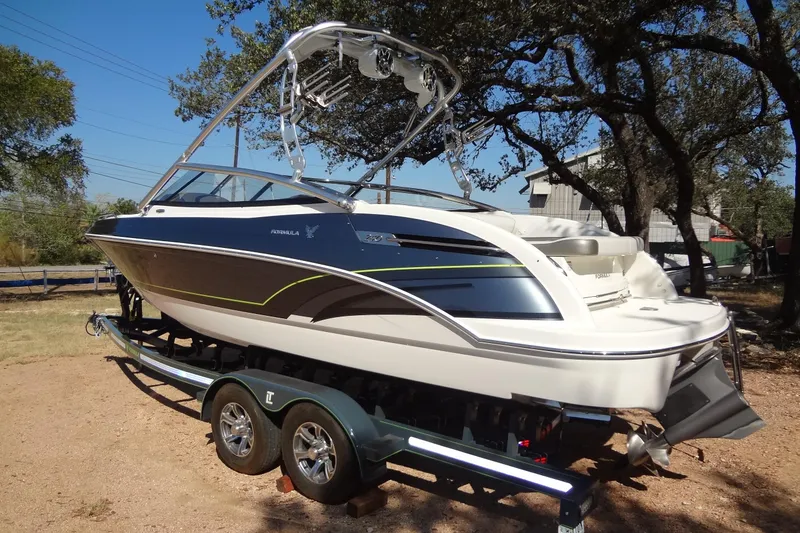 Slide: The Image of 2020 Formula 240 Bowrider boat on trailer, parked in driveway under clear sky. - 4