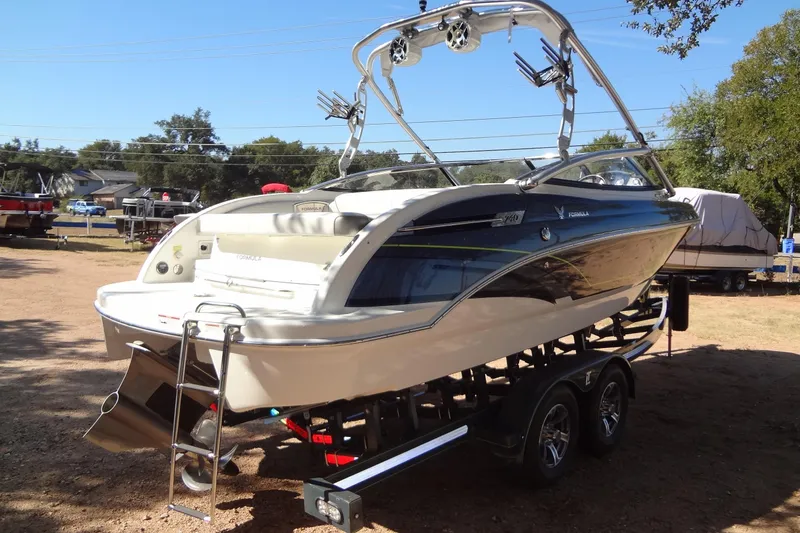 Slide: The Image of 2020 Formula 240 Bowrider boat on trailer, parked outdoors with trees in background. - 6