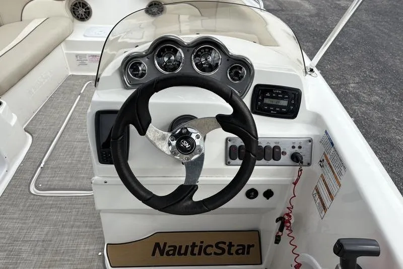 Slide: The Image of 2022 NauticStar 203 SC boat interior with steering wheel and cushioned seating. - 16