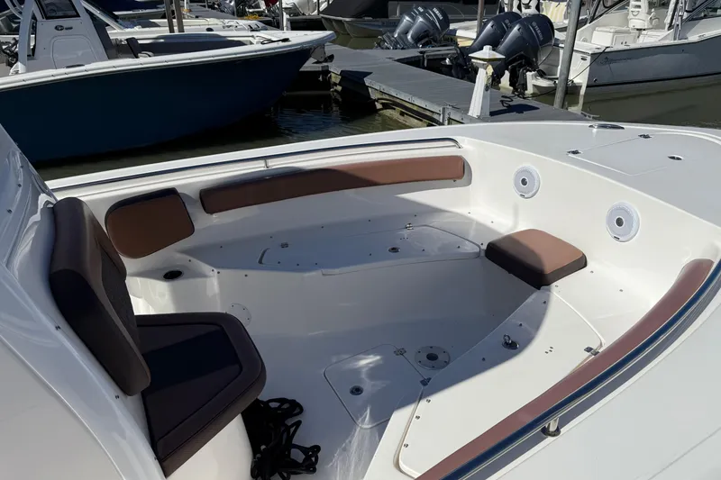 Slide: The Image of 2017 Tidewater 252 CC Adventure boat interior with cushioned seating and docked boats in background. - 2