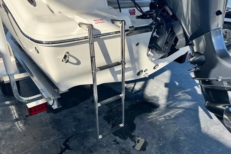 Slide: The Image of 2026 Key West 189 FS boat with ladder and motor, parked on a trailer. - 7