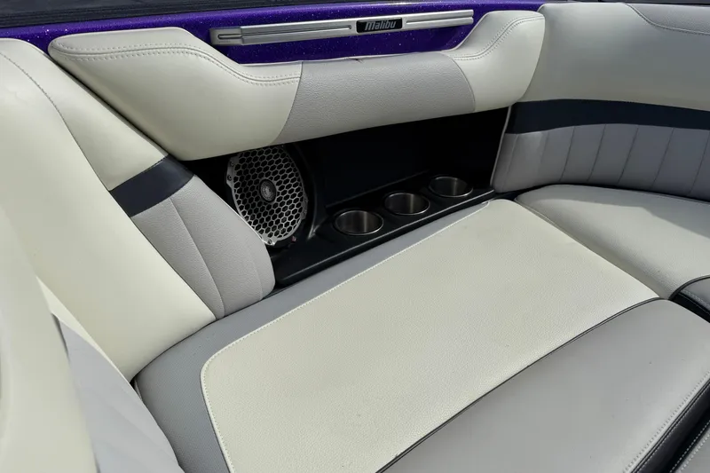 Slide: The Image of 2015 Malibu Wakesetter 24 MXZ interior with white and gray seating, cup holders, and speaker. - 16