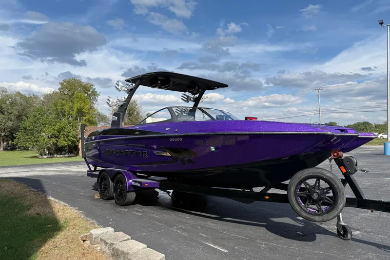 Slide: The Image of 2015 Malibu Wakesetter 24 MXZ boat in vibrant purple on a trailer, parked outdoors. - 3