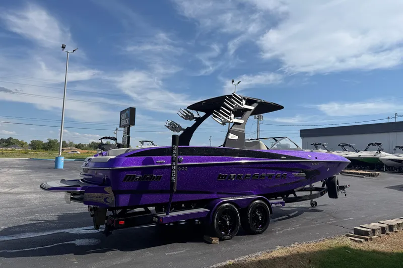 Slide: The Image of 2015 Malibu Wakesetter 24 MXZ boat in vibrant purple, parked outdoors under a clear sky. - 5