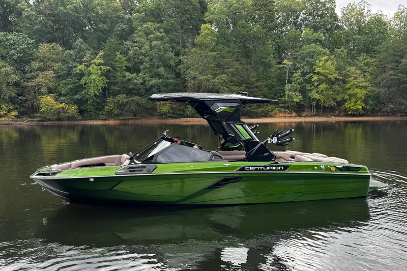 Slide: The Image of 2026 Centurion Ri245 boat in green on a calm lake with forest backdrop. - 4