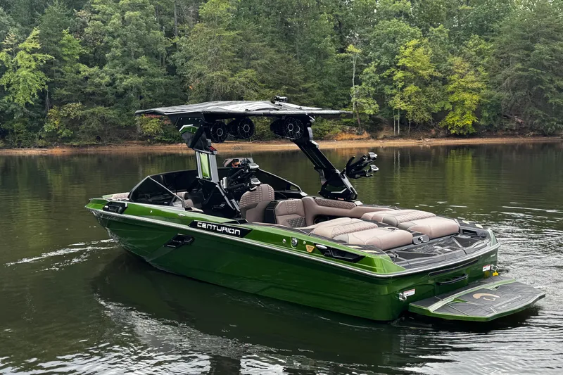 Slide: The Image of 2026 Centurion Ri245 boat in green on a calm lake, surrounded by lush trees. - 5