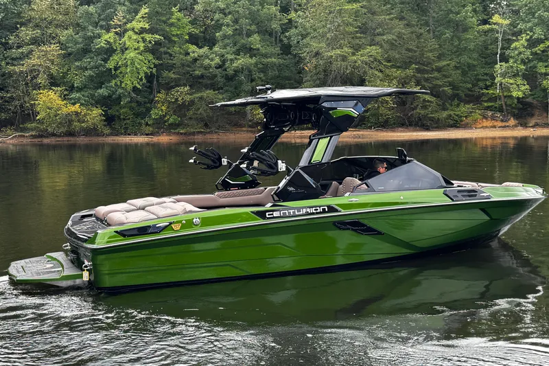 Slide: The Image of 2026 Centurion Ri245 boat in green on a calm lake with forest backdrop. - 7