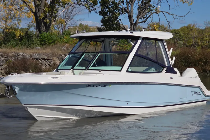The Image of 2024 Boston Whaler 280 Vantage boat on calm water, surrounded by autumn trees. - 0