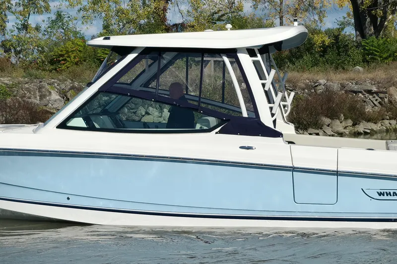 Slide: The Image of 2024 Boston Whaler 280 Vantage boat cruising on a sunny day near rocky shoreline. - 3