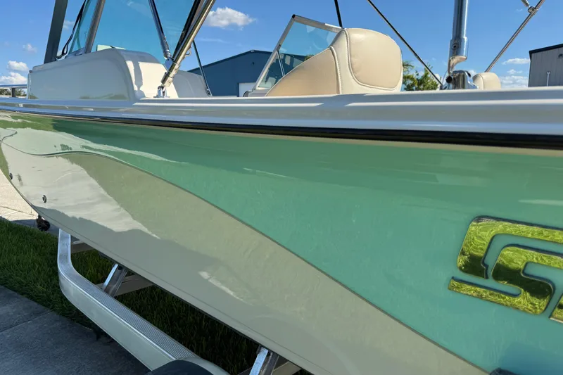 Slide: The Image of 2020 Carolina Skiff 21 LS DC boat with green and white exterior, parked outdoors. - 18