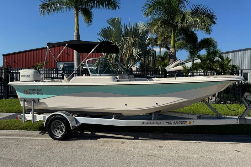 Slide: The Image of 2020 Carolina Skiff 21 LS DC boat on trailer, parked near palm trees. - 2