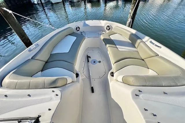 Slide: The Image of 2007 Sea Ray 240 Sundeck boat interior with cushioned seating, docked by the water. - 11