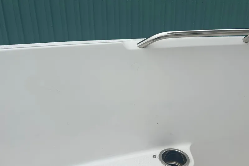 Slide: The Image of 2023 Robalo R180 Center Console boat with T-top against a teal building. - 40