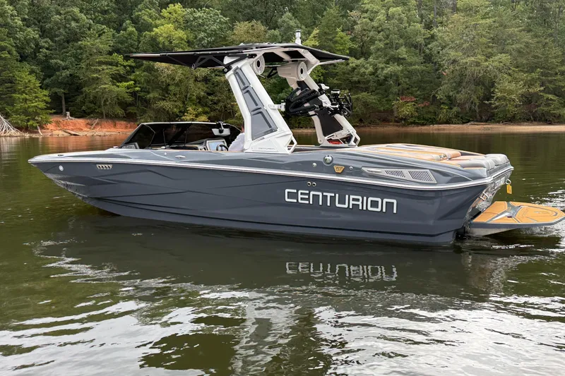 Slide: The Image of 2026 Centurion Nv233 boat on a calm lake, surrounded by lush greenery. - 11