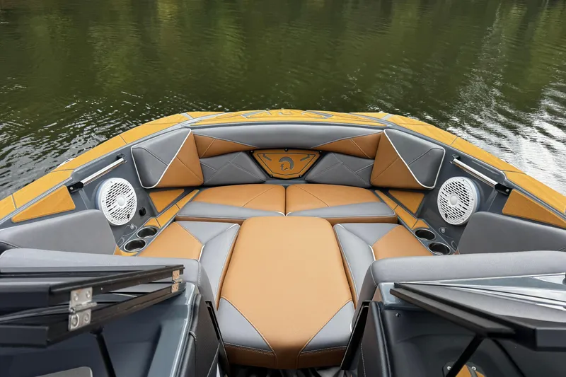 Slide: The Image of 2026 Centurion Nv233 boat interior with stylish seating and speakers on a calm lake. - 23