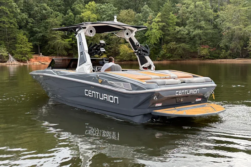 Slide: The Image of 2026 Centurion Nv233 boat cruising on a serene lake surrounded by lush greenery. - 4