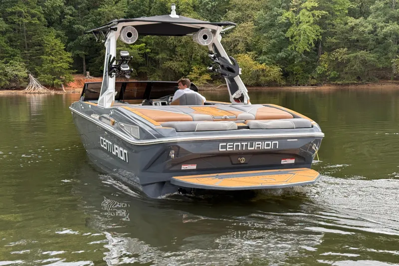 Slide: The Image of 2026 Centurion Nv233 boat cruising on a calm lake surrounded by lush trees. - 5