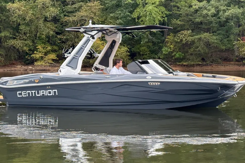 Slide: The Image of 2026 Centurion Nv233 boat on calm water, surrounded by lush greenery. - 8