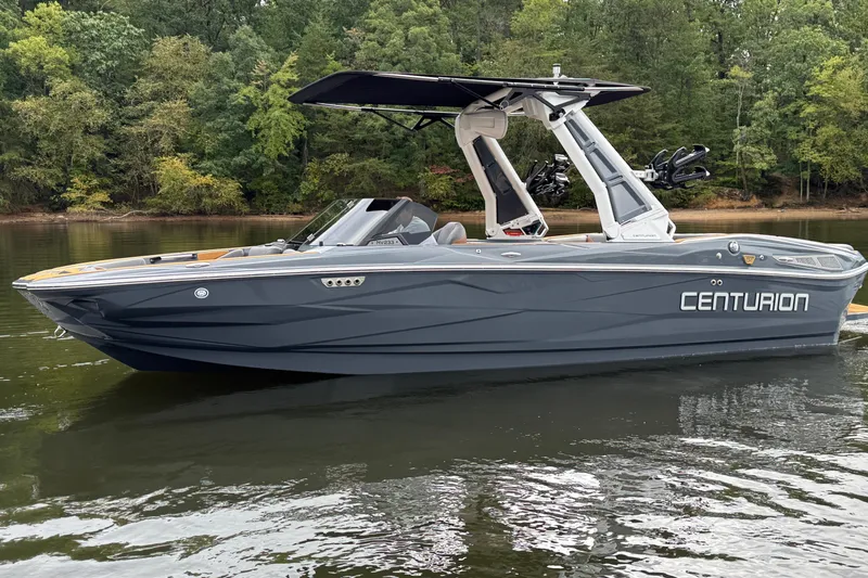 Slide: The Image of 2026 Centurion Nv233 boat on calm water, surrounded by lush green trees. - 9