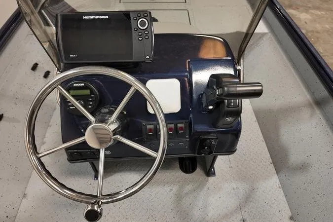 Slide: The Image of 2024 SeaArk Shadow 18 t boat dashboard with steering wheel and navigation system. - 8