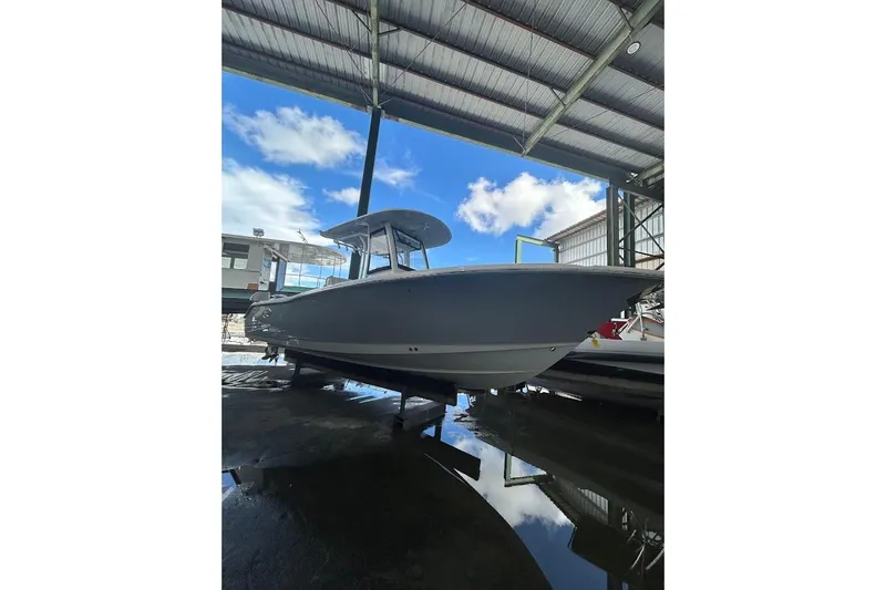 Slide: The Image of 2023 Seahunt SXS boat in a covered storage area, clear sky background. - 4