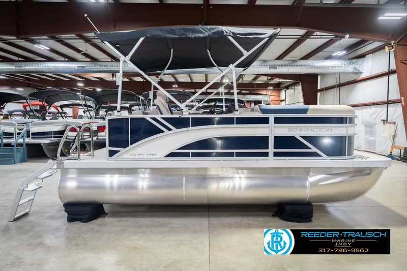 Slide: The Image of 2026 Bennington 168 SLJ pontoon boat in showroom, featuring sleek design and canopy. - 7