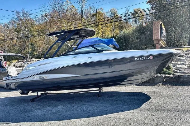 The Image of 2023 Monterey M6 boat on display outdoors, surrounded by trees and clear sky. - 1