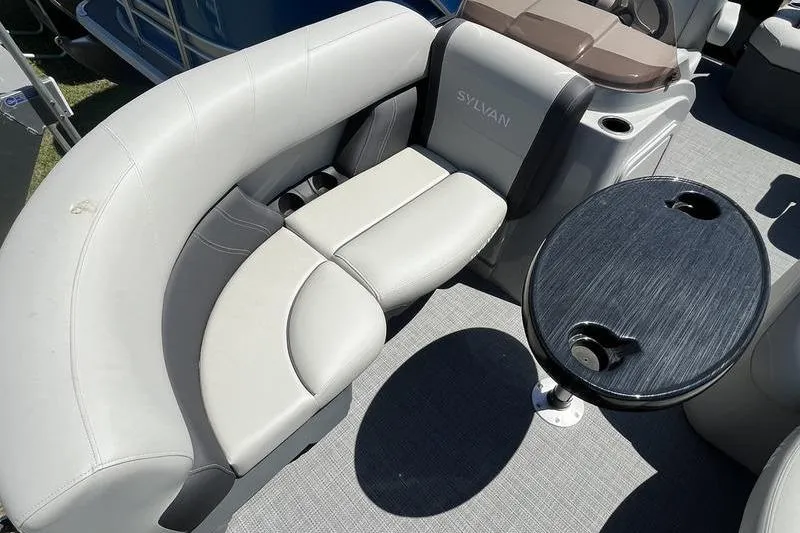 Slide: The Image of 2025 Sylvan Mirage 820 CLZ DH boat interior with curved seating and round table. - 13