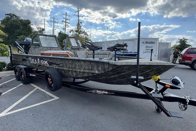 The Image of 2026 SeaArk EasyCat boat with camouflage design on a trailer, parked outdoors. - 2