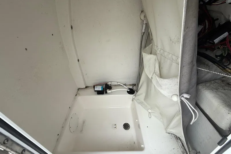 Slide: The Image of 2017 Tidewater 230 LXF boat interior showing storage compartment and pump system. - 20