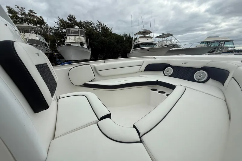 Slide: The Image of 2017 Tidewater 230 LXF boat interior with white seating and cup holders, docked near other boats. - 6