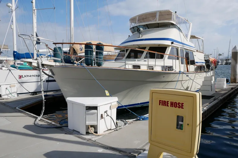 Slide: The Image of 1985 Tollycraft 48 Cockpit Motor Yacht docked at marina with fire hose nearby. - 1