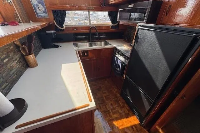 Slide: The Image of 1985 Tollycraft 48 Cockpit Motor Yacht kitchen with wood cabinetry and modern appliances. - 23