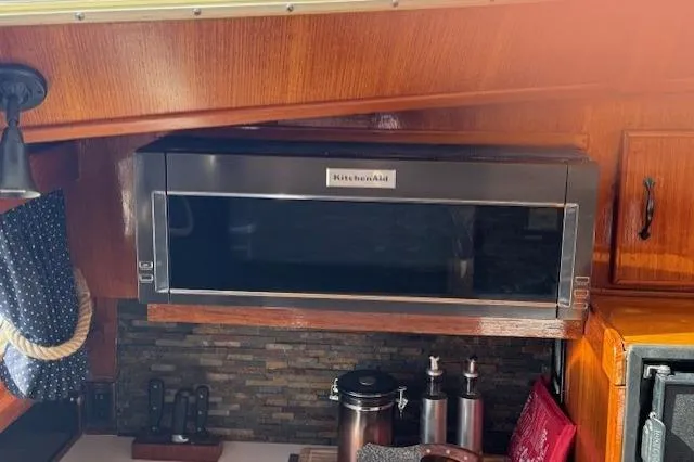Slide: The Image of Kitchen area of 1985 Tollycraft 48 Cockpit Motor Yacht with microwave and wooden cabinetry. - 24
