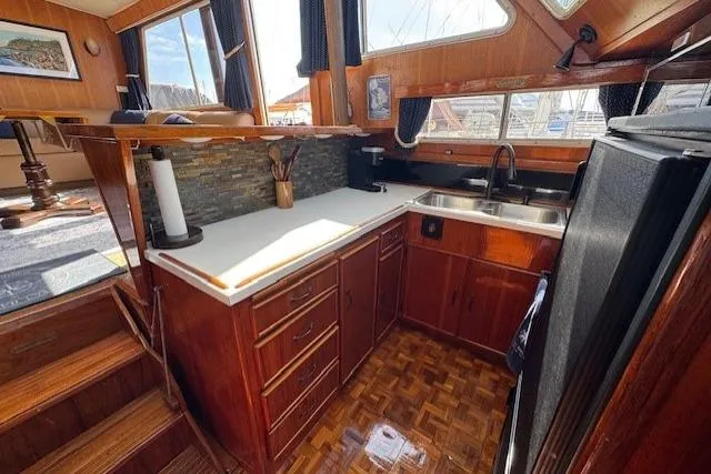 Slide: The Image of 1985 Tollycraft 48 Cockpit Motor Yacht kitchen with wood cabinetry and modern appliances. - 26