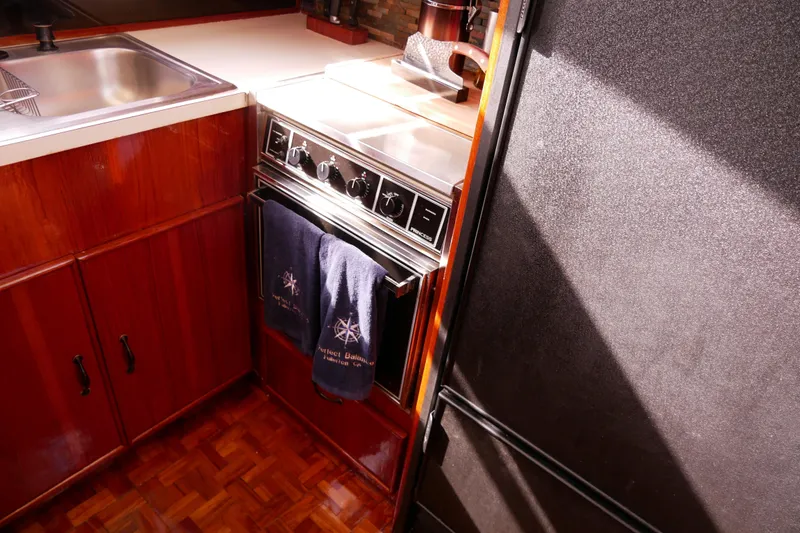 Slide: The Image of 1985 Tollycraft 48 Cockpit Motor Yacht kitchen with stove, sink, and wooden cabinetry. - 29