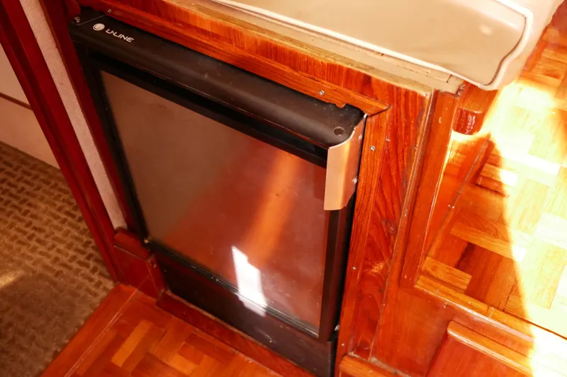 Slide: The Image of 1985 Tollycraft 48 Cockpit Motor Yacht interior with U-Line fridge and wood paneling. - 30